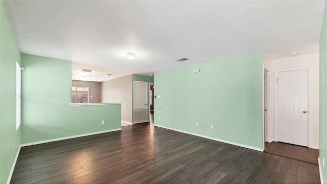 spare room with dark wood-style floors, visible vents, and baseboards