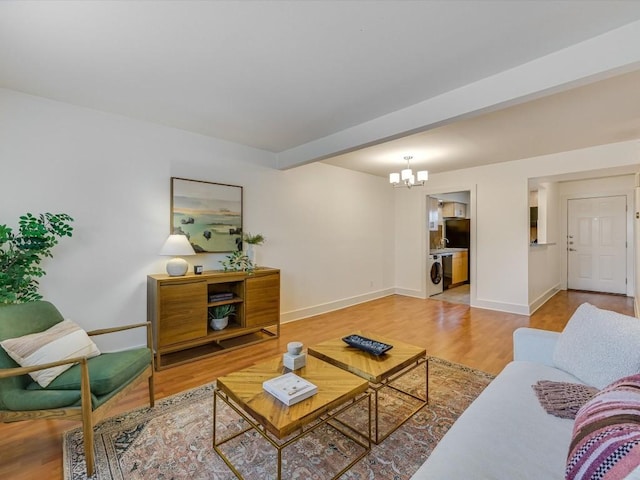 living room featuring an inviting chandelier, washer / clothes dryer, and hardwood / wood-style flooring