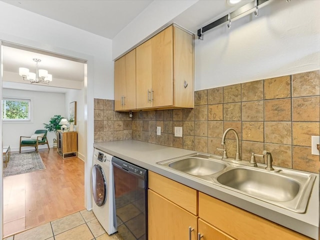 kitchen featuring decorative light fixtures, washer / dryer, black dishwasher, sink, and decorative backsplash