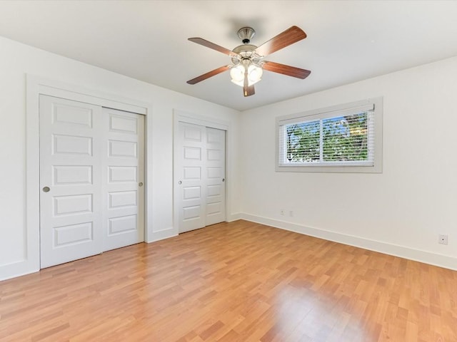 unfurnished bedroom with ceiling fan, two closets, and light hardwood / wood-style floors