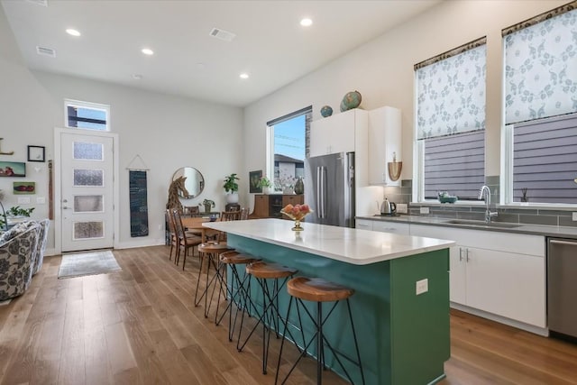 kitchen featuring sink, a kitchen breakfast bar, stainless steel appliances, a center island, and white cabinets