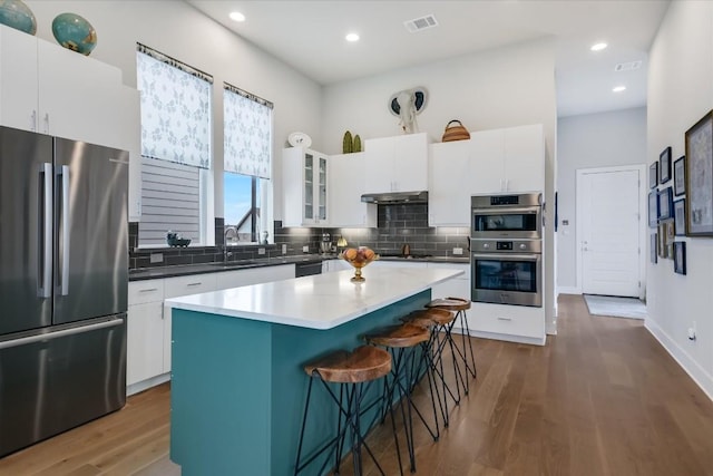 kitchen featuring sink, white cabinetry, backsplash, a center island, and black appliances