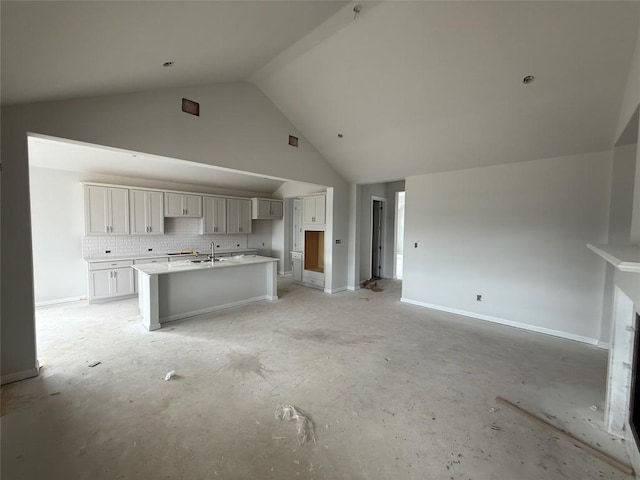 kitchen featuring tasteful backsplash, sink, high vaulted ceiling, and an island with sink