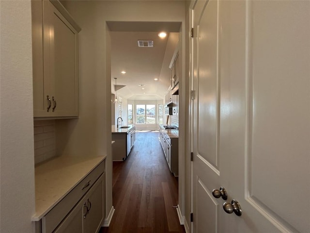 corridor with visible vents, dark wood finished floors, a sink, and recessed lighting