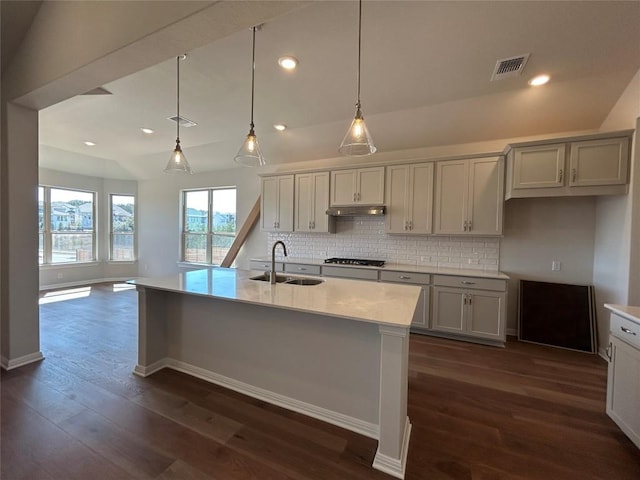 kitchen featuring dark wood-style floors, visible vents, a sink, gas cooktop, and under cabinet range hood