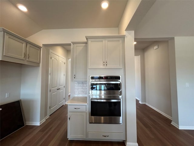 kitchen featuring double oven, baseboards, dark wood-style floors, and tasteful backsplash