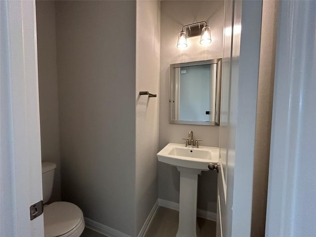 bathroom with baseboards, a sink, and toilet