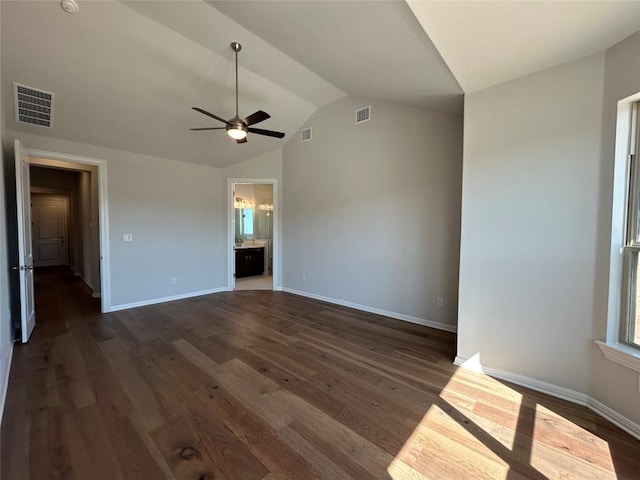 empty room featuring lofted ceiling, dark wood-type flooring, visible vents, and baseboards