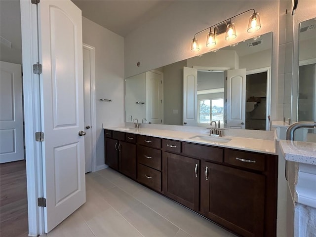 bathroom featuring double vanity, visible vents, a sink, and tile patterned floors