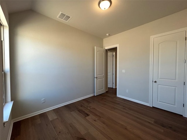 unfurnished bedroom featuring baseboards, visible vents, and dark wood finished floors