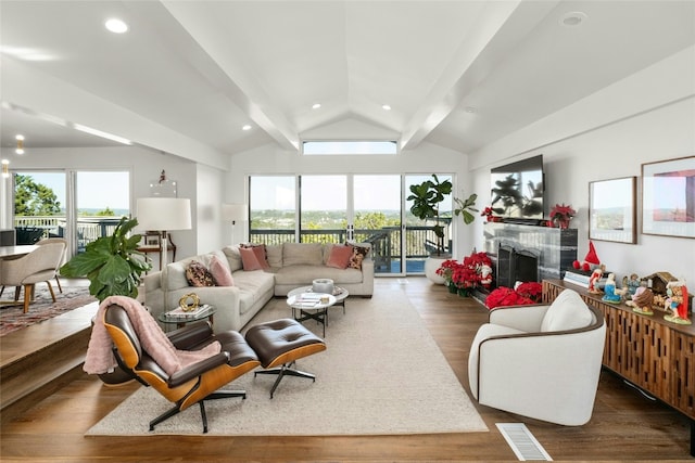 living room featuring dark hardwood / wood-style flooring, lofted ceiling with beams, and a wealth of natural light