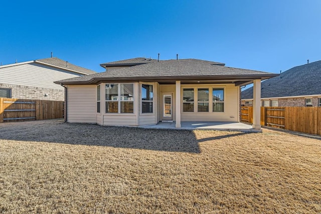 back of house featuring a shingled roof, a patio area, and a fenced backyard