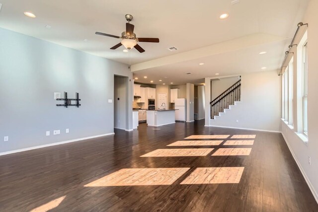 unfurnished living room with dark wood-type flooring and ceiling fan