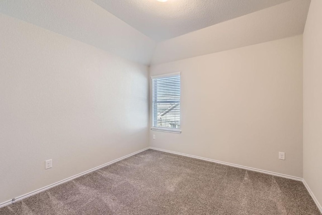 empty room with a textured ceiling, baseboards, vaulted ceiling, and carpet flooring