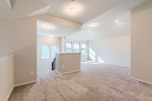 unfurnished room with lofted ceiling, light colored carpet, and a textured ceiling