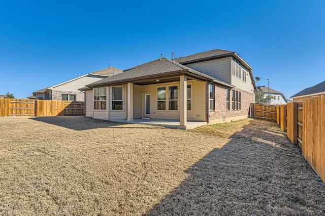 rear view of property with a patio, brick siding, and a fenced backyard