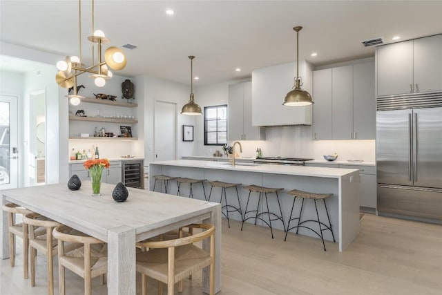 kitchen featuring gray cabinets, a breakfast bar, wine cooler, hanging light fixtures, and stainless steel appliances