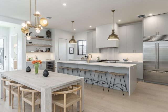 1702 Bauerle Ave, Austin, TX 78704 - kitchen featuring built in fridge, beverage cooler, light countertops, an island with sink, and light wood finished floors