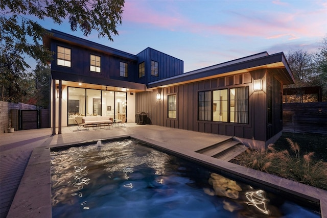 1702 Bauerle Ave, Austin, TX 78704 - back of house at dusk featuring an outdoor hangout area, board and batten siding, a pool, and a patio area