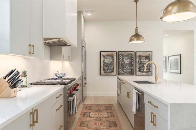 kitchen featuring premium appliances, decorative light fixtures, sink, and white cabinets