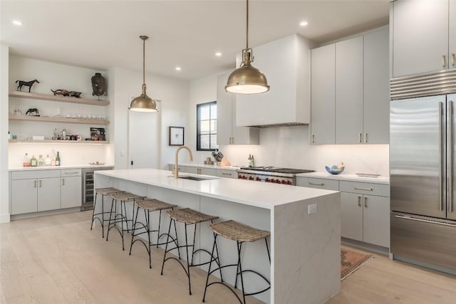 1702 Bauerle Ave, Austin, TX 78704 - kitchen featuring appliances with stainless steel finishes, wine cooler, light wood-style floors, a kitchen bar, and recessed lighting