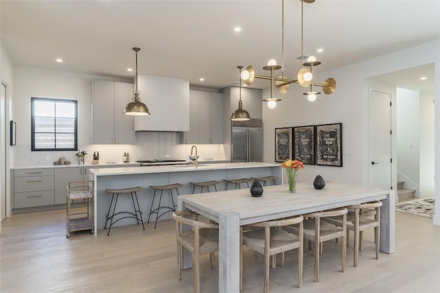 kitchen with built in fridge, gray cabinets, decorative light fixtures, a breakfast bar area, and a large island