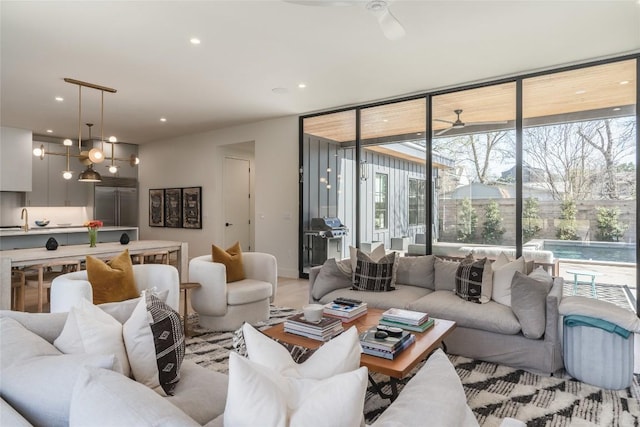 living room with floor to ceiling windows, sink, ceiling fan with notable chandelier, and plenty of natural light