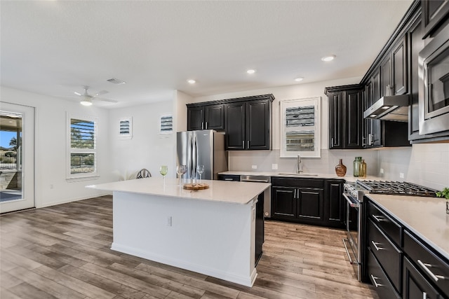 kitchen featuring appliances with stainless steel finishes, tasteful backsplash, sink, a center island, and light hardwood / wood-style floors