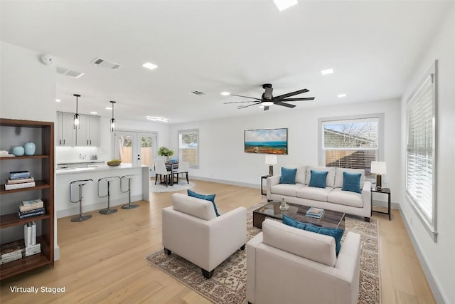 living room with light hardwood / wood-style floors, french doors, and ceiling fan