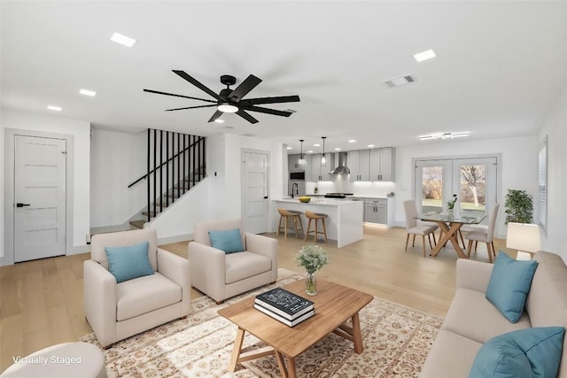 living room with ceiling fan, light wood-type flooring, and french doors