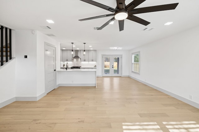 unfurnished living room with french doors, ceiling fan, and light hardwood / wood-style flooring