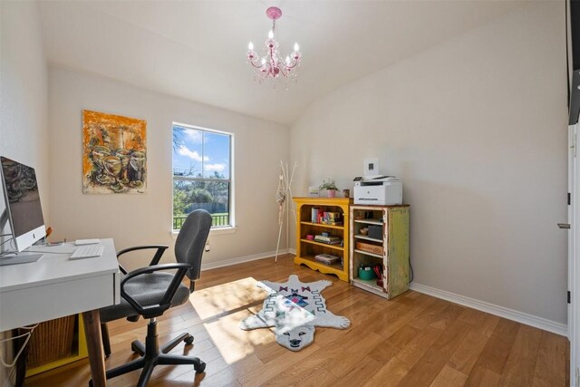 office space with an inviting chandelier, vaulted ceiling, and light hardwood / wood-style floors