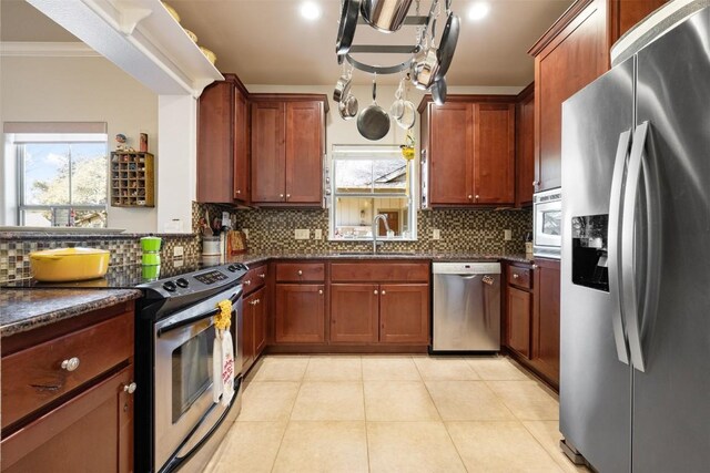 kitchen with sink, light tile patterned floors, appliances with stainless steel finishes, backsplash, and ornamental molding