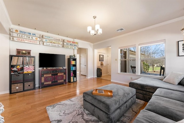 living area with visible vents, an inviting chandelier, wood finished floors, and ornamental molding