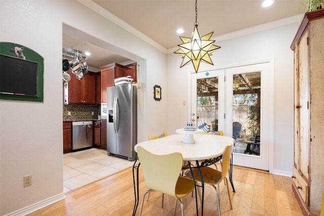 dining area featuring light wood-type flooring, recessed lighting, an inviting chandelier, crown molding, and baseboards