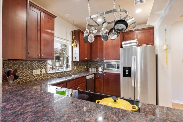 kitchen with sink, backsplash, dark stone counters, and appliances with stainless steel finishes