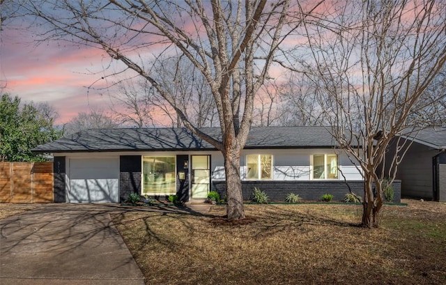 ranch-style home featuring a garage and a lawn