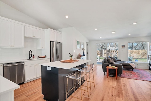 kitchen featuring white cabinetry, an island with sink, appliances with stainless steel finishes, and lofted ceiling