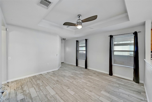 unfurnished room featuring light hardwood / wood-style flooring, ceiling fan, and a tray ceiling