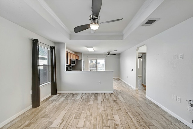 empty room with crown molding, a tray ceiling, light hardwood / wood-style flooring, and ceiling fan