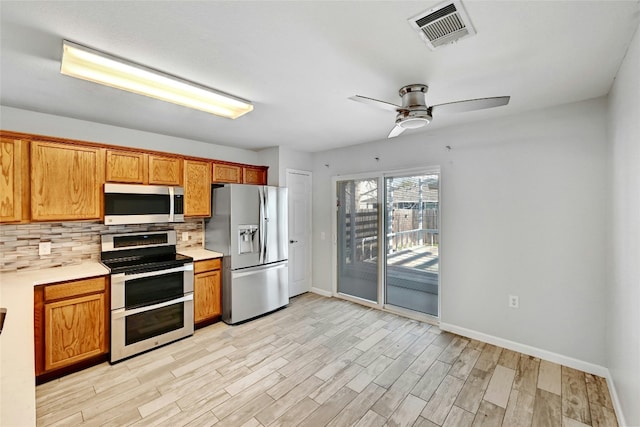 kitchen featuring ceiling fan, appliances with stainless steel finishes, backsplash, and light wood-type flooring