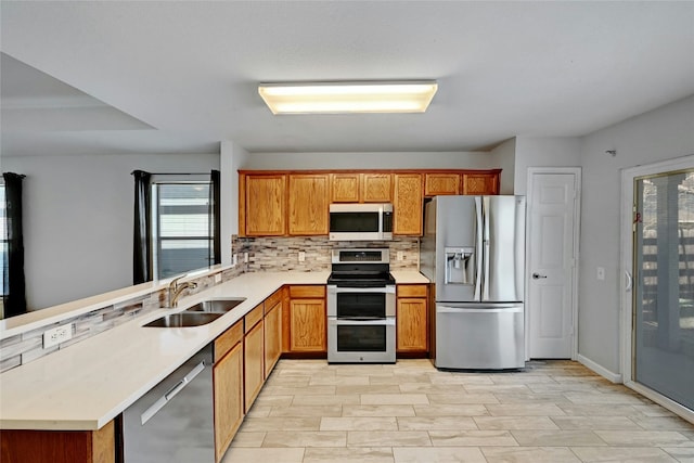 kitchen with stainless steel appliances, sink, backsplash, and kitchen peninsula