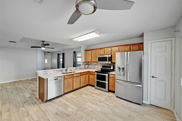 7405 Cayenne Ln, Austin, TX 78741 - kitchen with stainless steel appliances, a ceiling fan, a sink, a peninsula, and light countertops