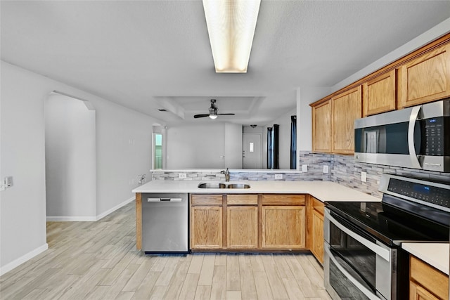 kitchen featuring appliances with stainless steel finishes, tasteful backsplash, sink, kitchen peninsula, and a raised ceiling