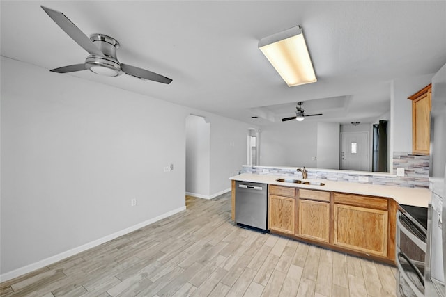 kitchen featuring sink, backsplash, stainless steel dishwasher, range, and light wood-type flooring