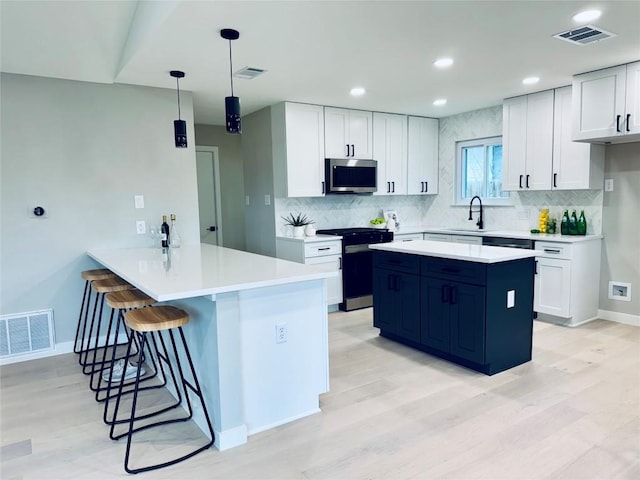 kitchen featuring range with gas stovetop, hanging light fixtures, kitchen peninsula, and white cabinets