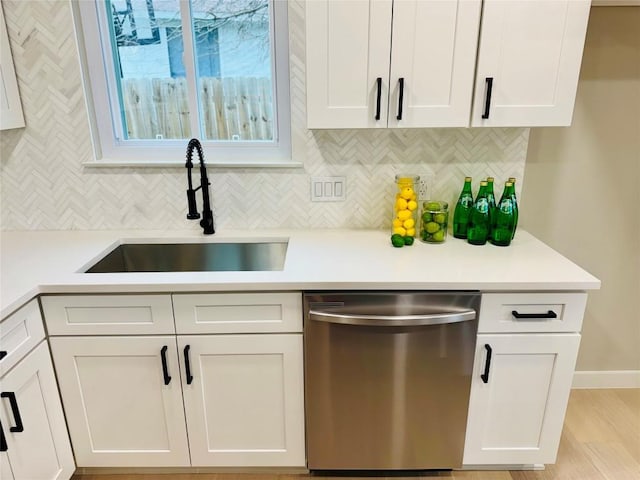 kitchen with white cabinetry, sink, stainless steel dishwasher, and decorative backsplash