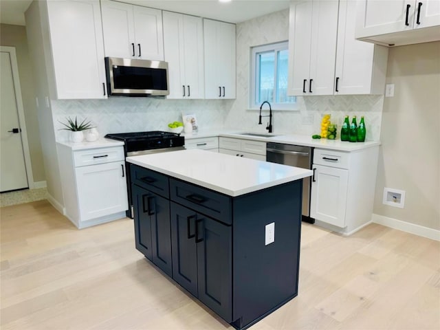 kitchen with appliances with stainless steel finishes, a center island, sink, and white cabinets