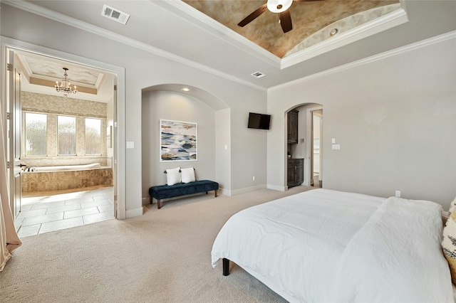 carpeted bedroom with ornamental molding, ceiling fan with notable chandelier, ensuite bathroom, and a tray ceiling