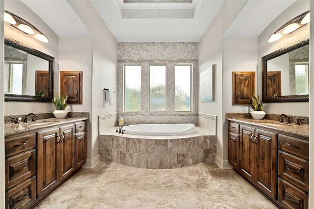 bathroom featuring a relaxing tiled tub, vanity, a tray ceiling, and crown molding